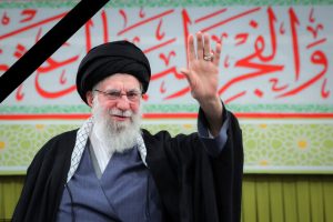 تصویر مقام معظم رهبری که ایستاده است و دستش را بالا برده است